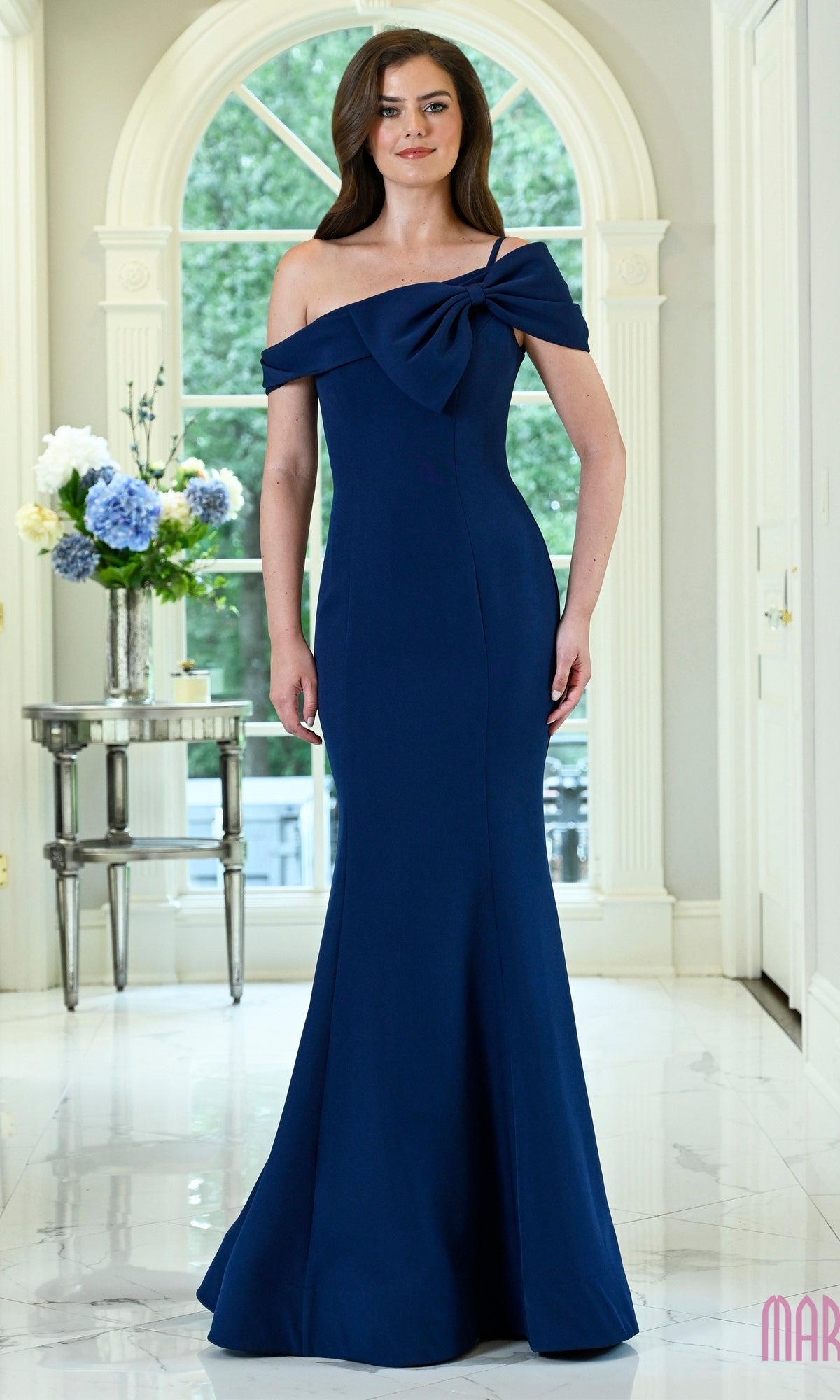 Navy off-the-shoulder Marsoni MV1432 evening gown in a crepe fabric, featuring a bow detail on the neckline and a floor-length mermaid silhouette.